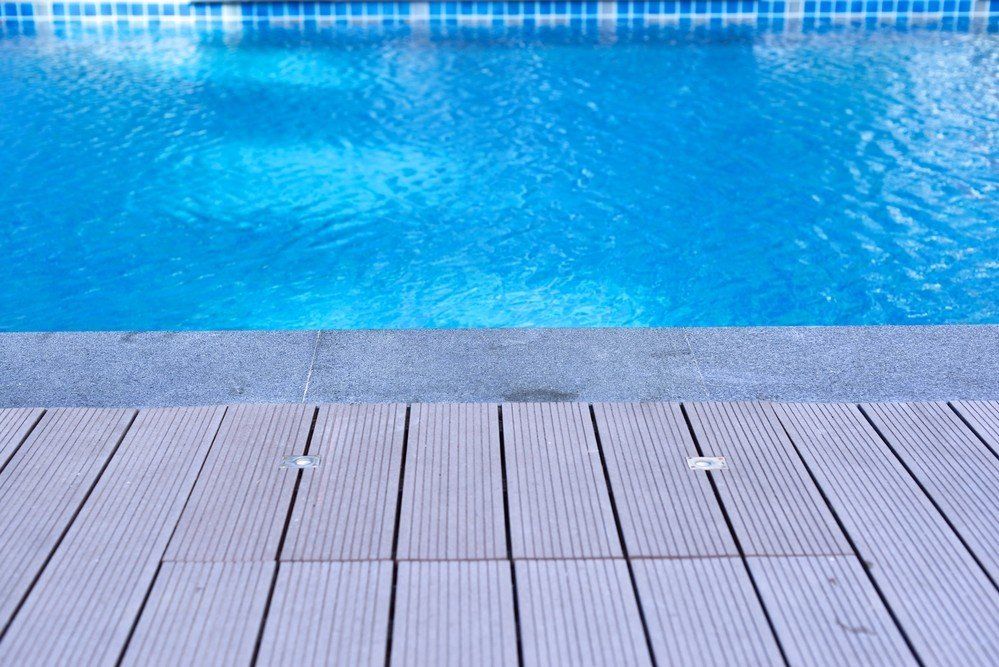Blue swimming pool with tiled deck in the foreground